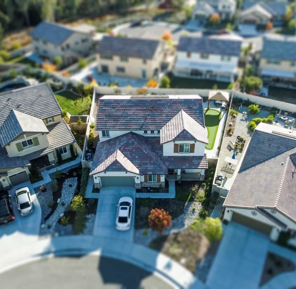 Aerial view of a suburban community with several modern houses, driveways, and landscaped yards on a curved street, perfect for those seeking the benefits of HOA's.